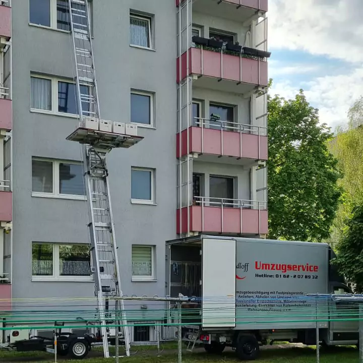 Umzugskartons werden mithilfe eines Möbellifts von der oberen Etage eines Hochhauses nach unten transportiert